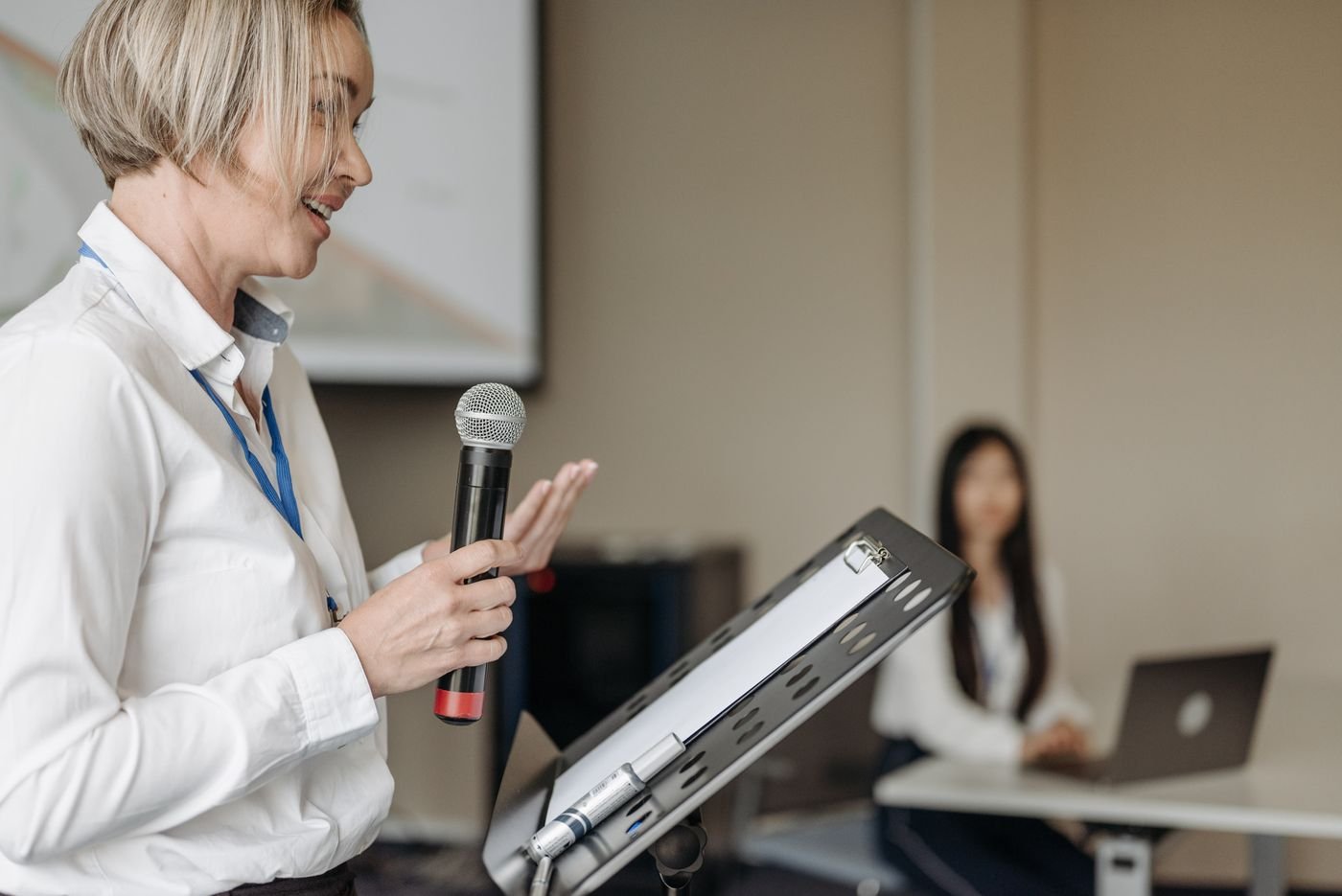Una presentadora con micrófono se dirige a un seminario profesional